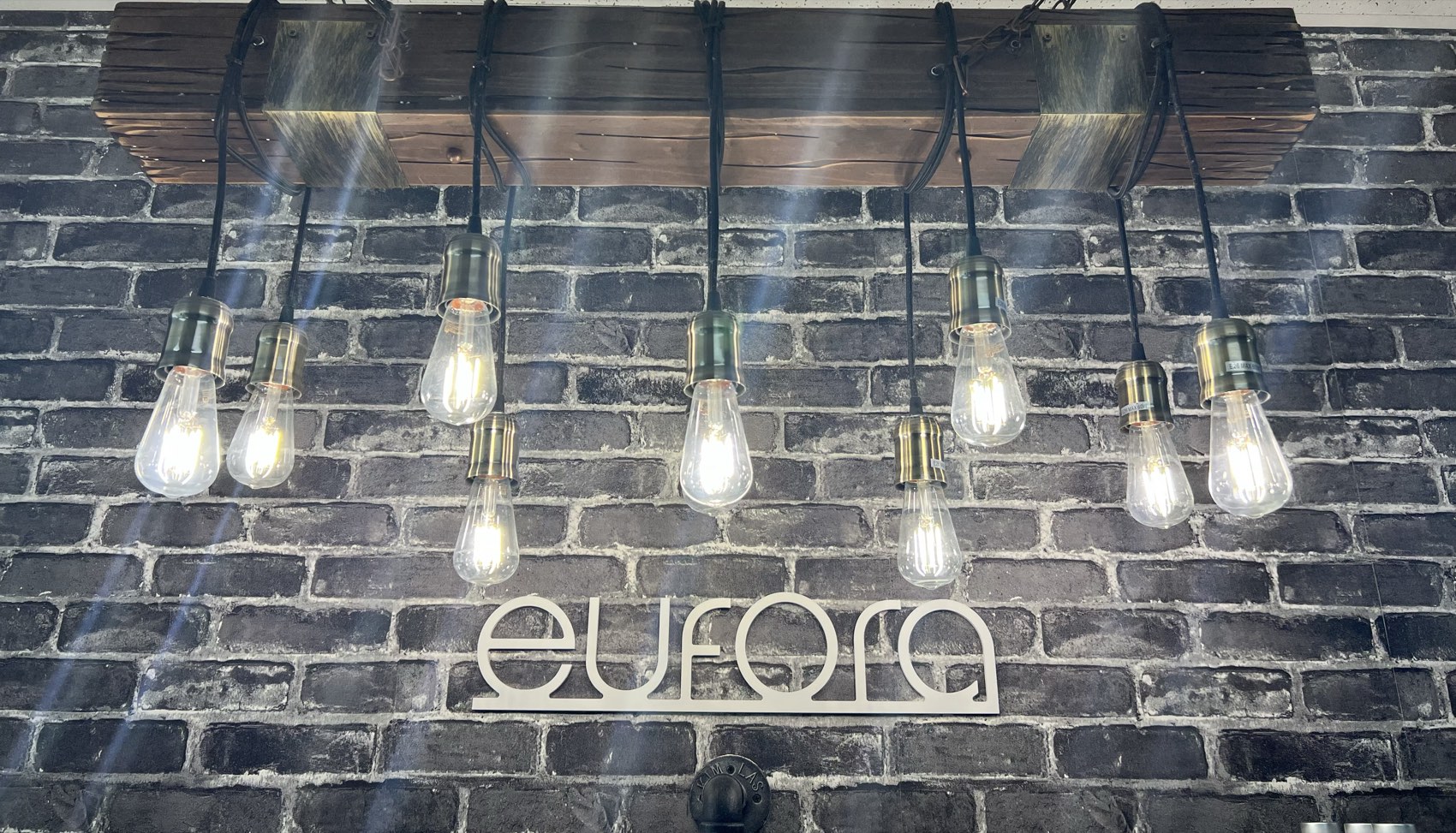 The illuminated Eufora sign and Edison-bulb lighting on the salon's brick wall