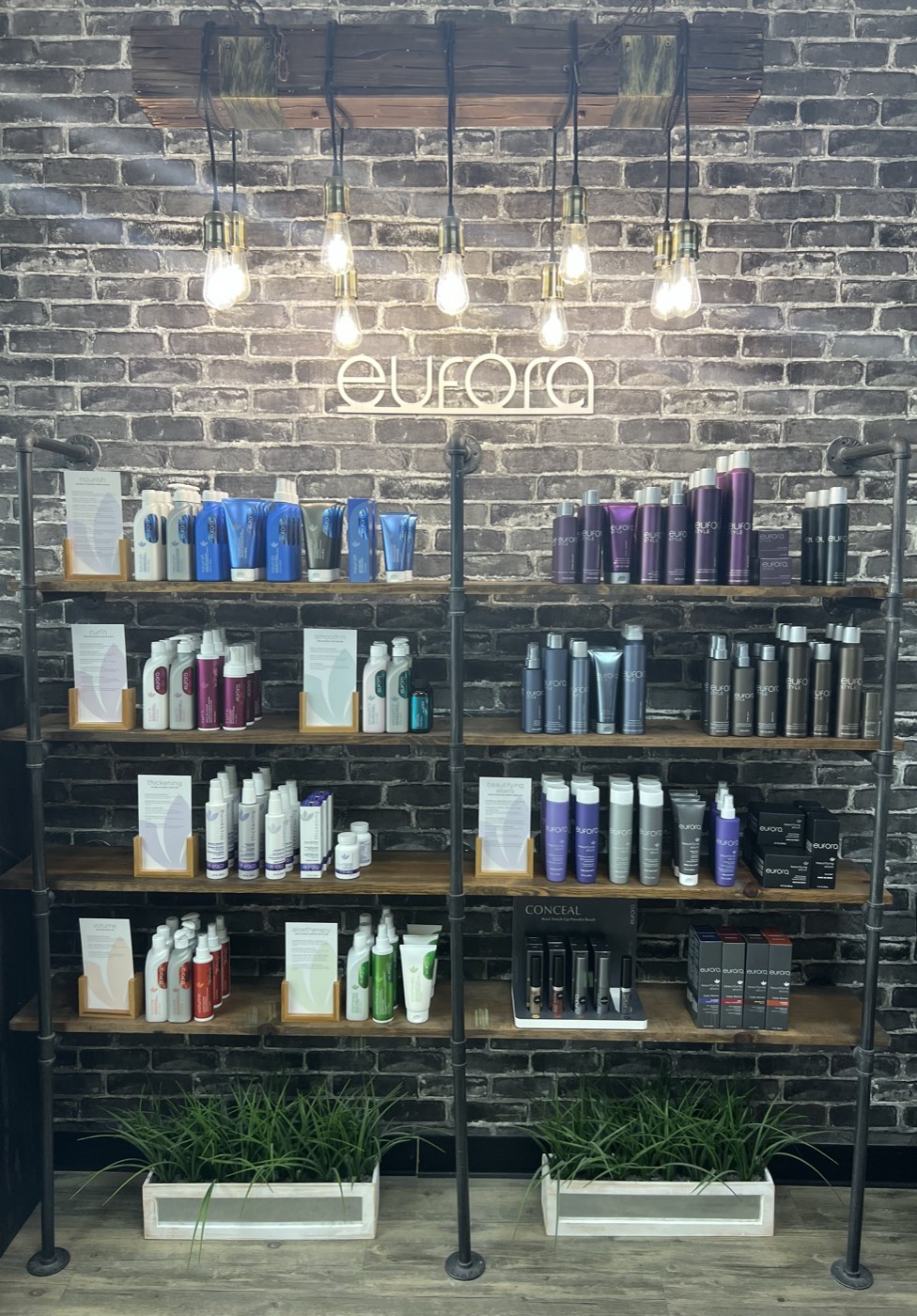 The Loft's full Eufora retail wall, stocked on reclaimed-wood and pipe shelving